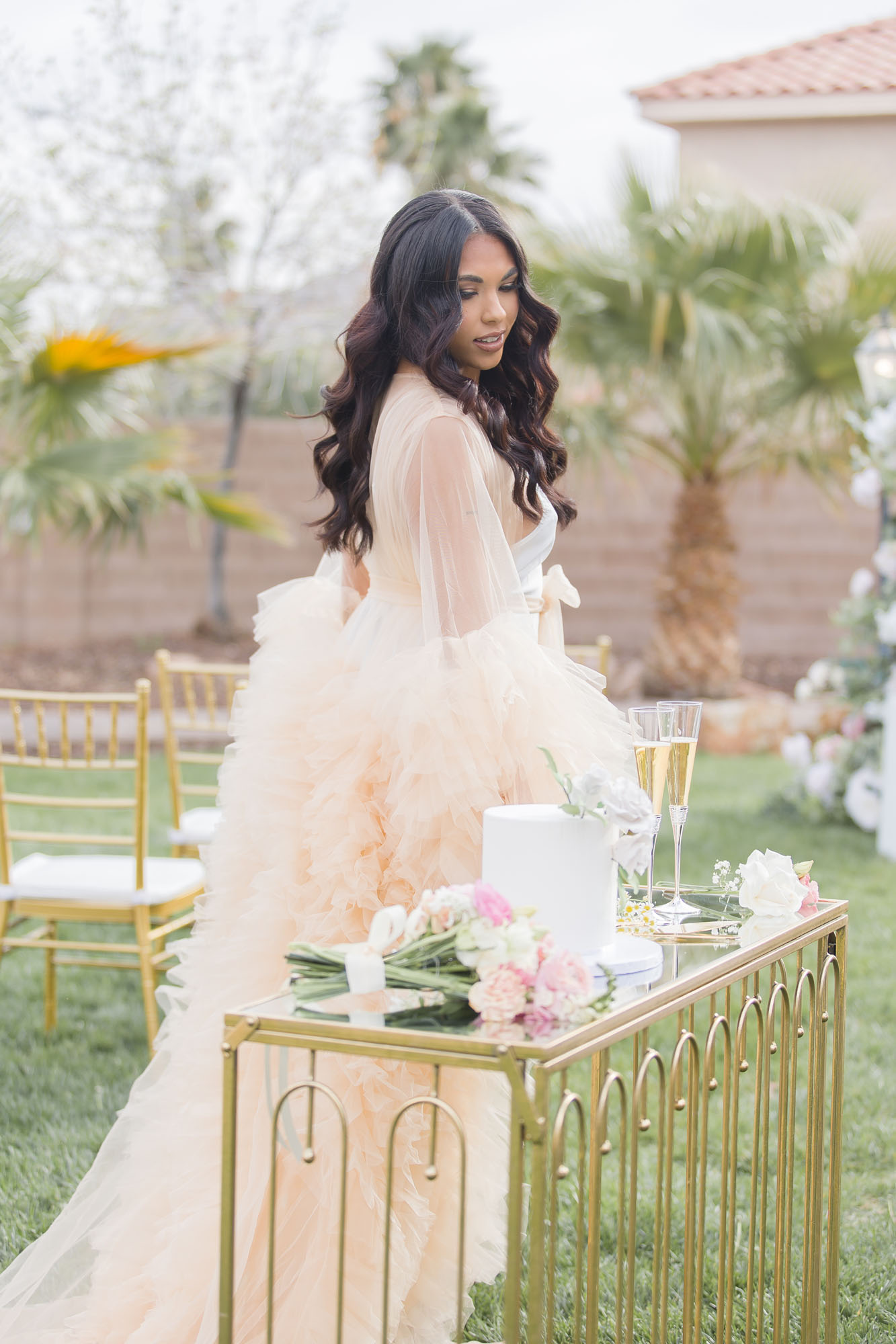 Beautiful bride thoughtfully runs hand along a cake table set up at her las vegas mansion wedding venues garden