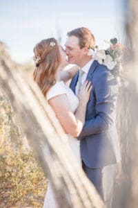 Newlyweds lean in for a kiss while hiding in the garden at their cactus joe's wedding