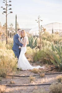 Newlyweds touch cheeks while hugging and smiling in a desert garden at their cactus joe's wedding