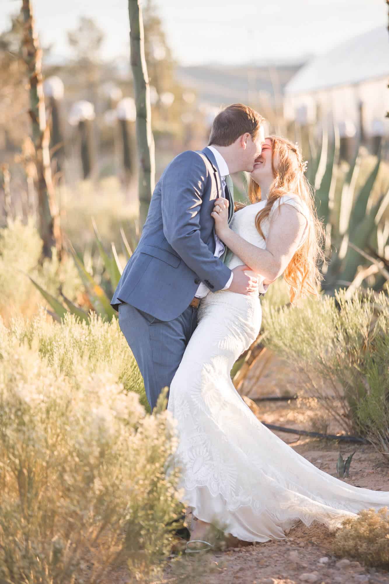 Newlyweds share a happy kiss in a desert garden at their cactus joe's wedding