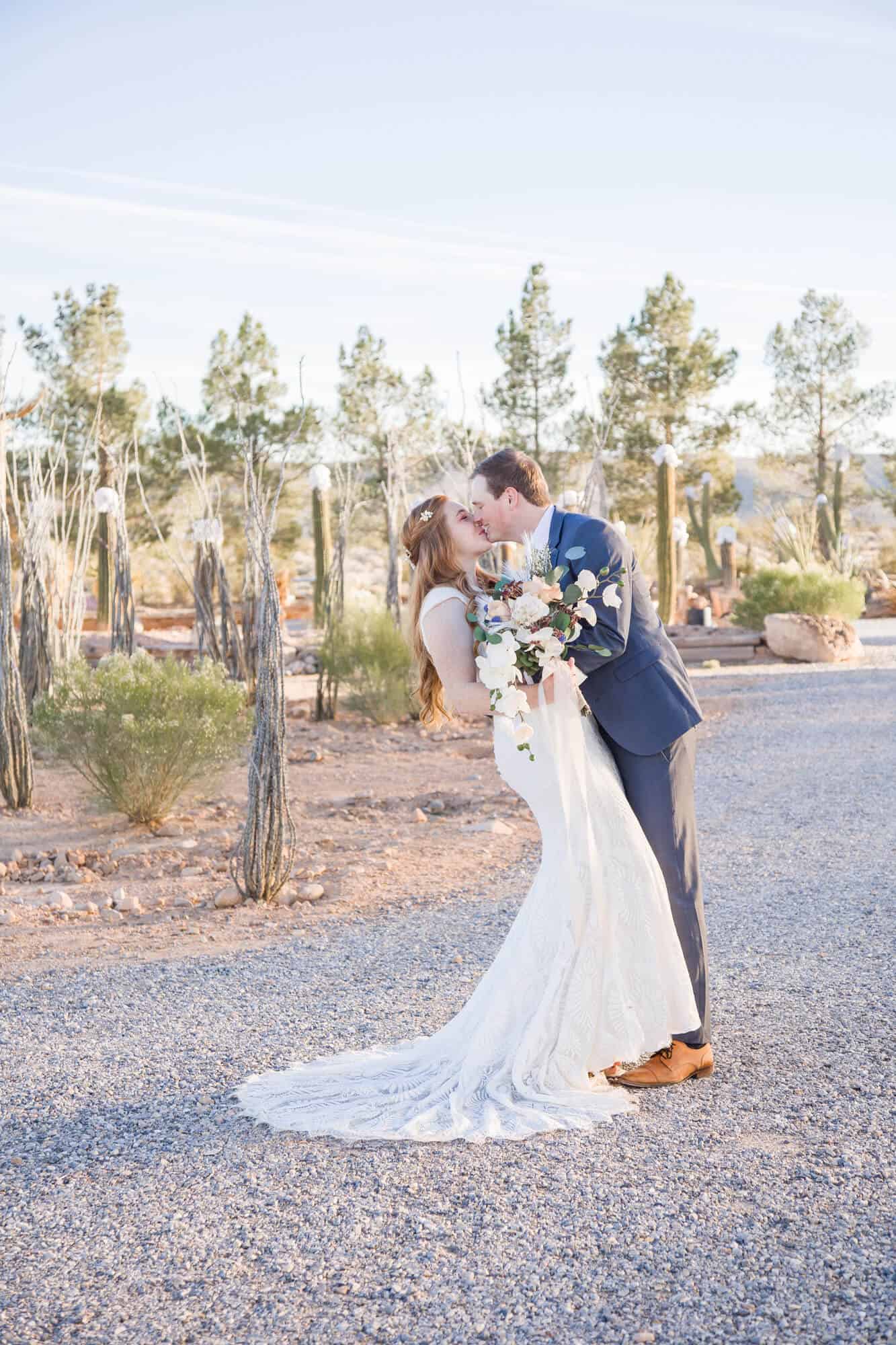 Newlyweds share a kiss in a gravel garden trail at the cactus joe's wedding venue