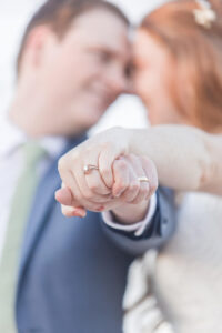 Details of newlyweds touching heads while holding their ring hands in front of them