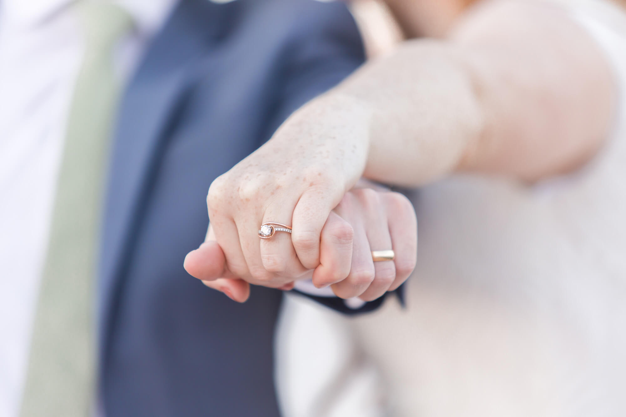 Details of newlyweds holding hands with their ring hands stretched in front of them