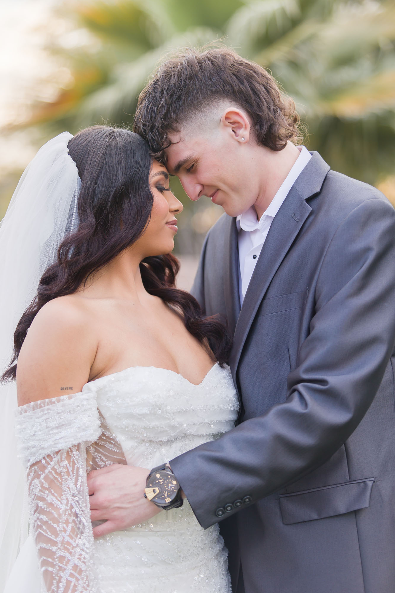 A bride and groom touch foreheads while hugging at their wedding in a garden at susnet