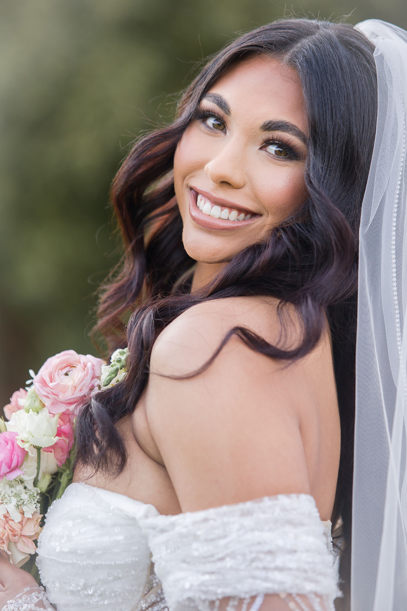 A bride smiles over her shoulder while holding her colorful bouquet