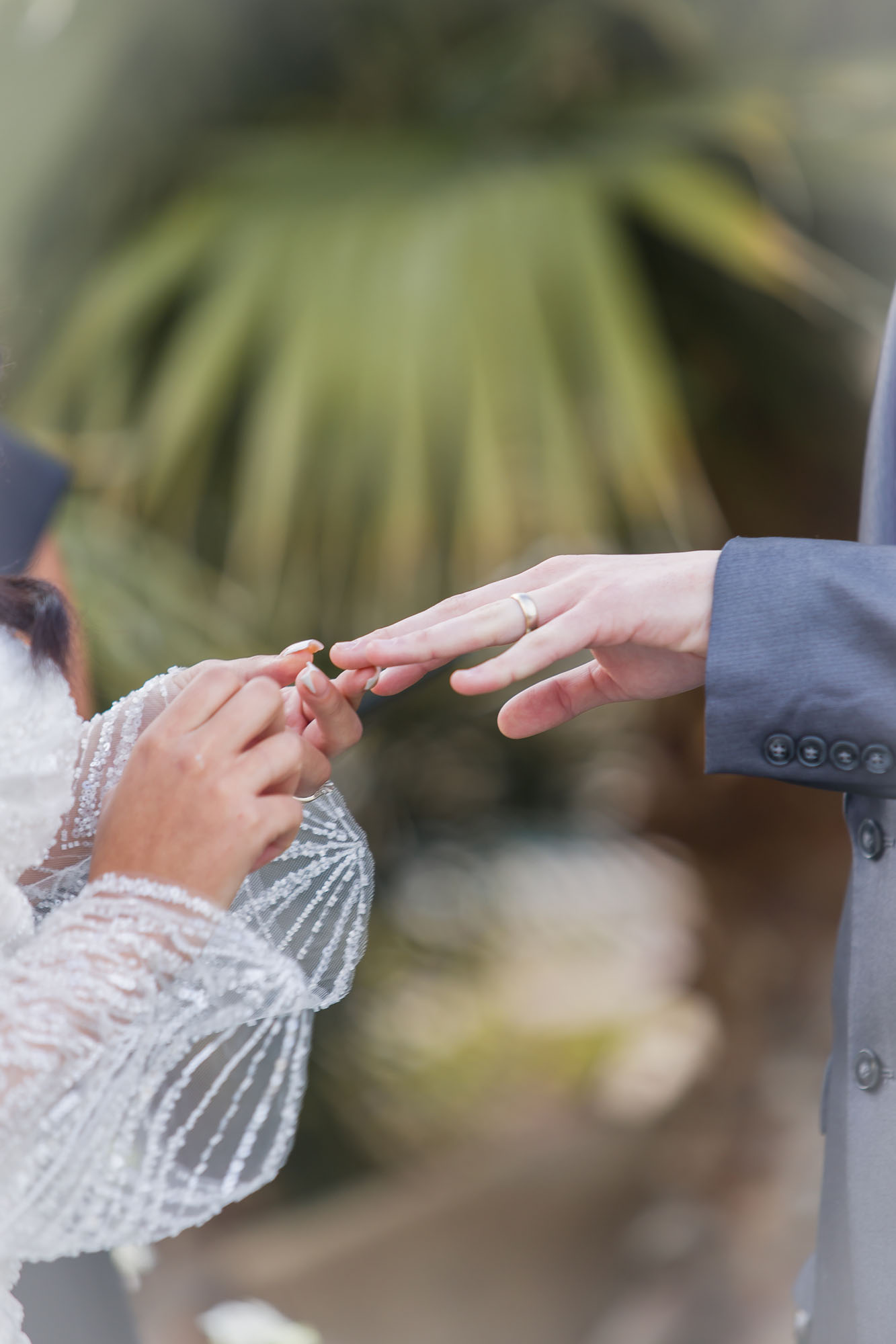 Details of a bride putting on her groom's ring during their ceremony at their las vegas country club wedding