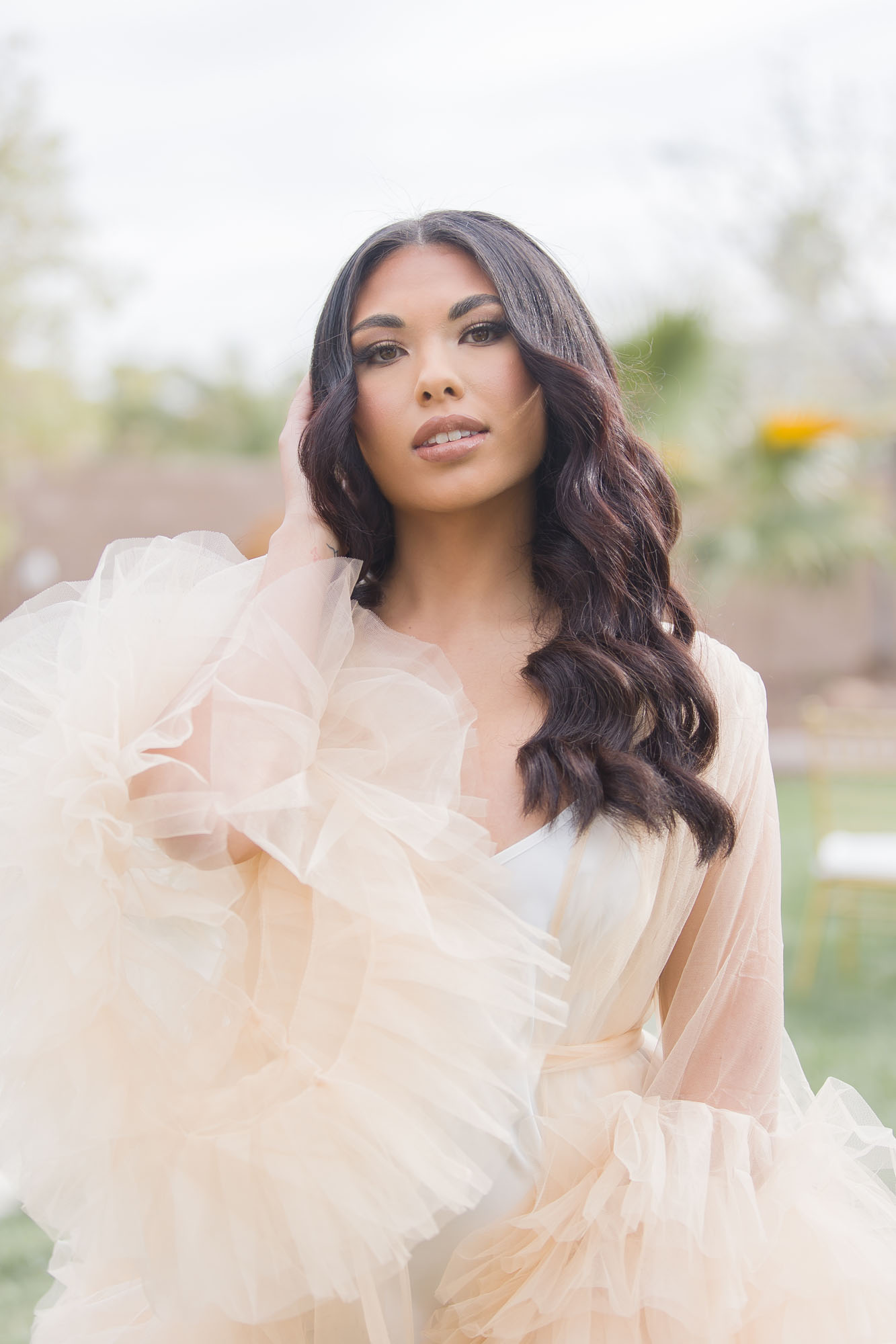 A bride in a cream and white dress walks through the gardens of her venue