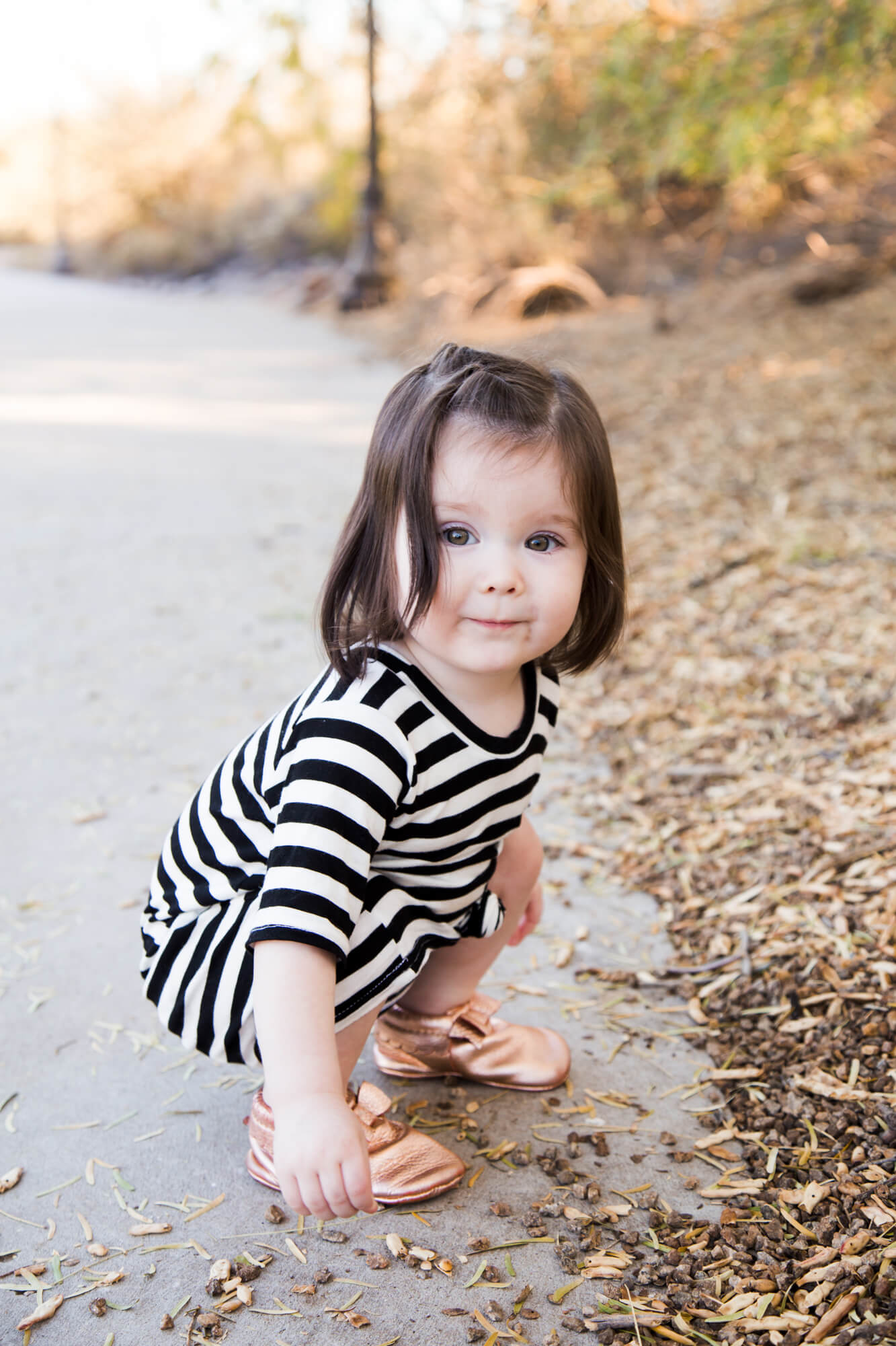 A young toddler girl explores a park sidewalk edge before finding playgrounds in las vegas