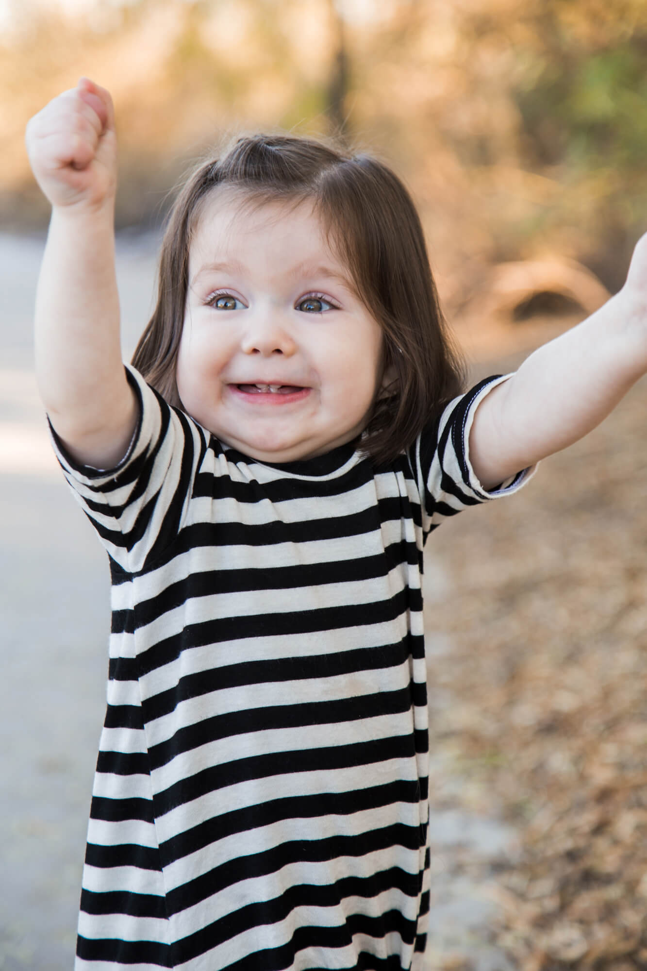 A toddler girl in a striped dress celebrates before visiting playgrounds in las vegas